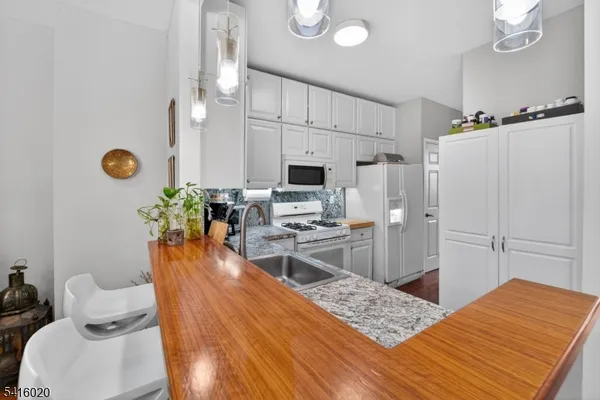 a living room with stainless steel appliances furniture a rug and a view of kitchen