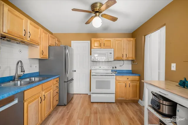 a kitchen with stainless steel appliances a stove a sink dishwasher a refrigerator and a stove with wooden floor