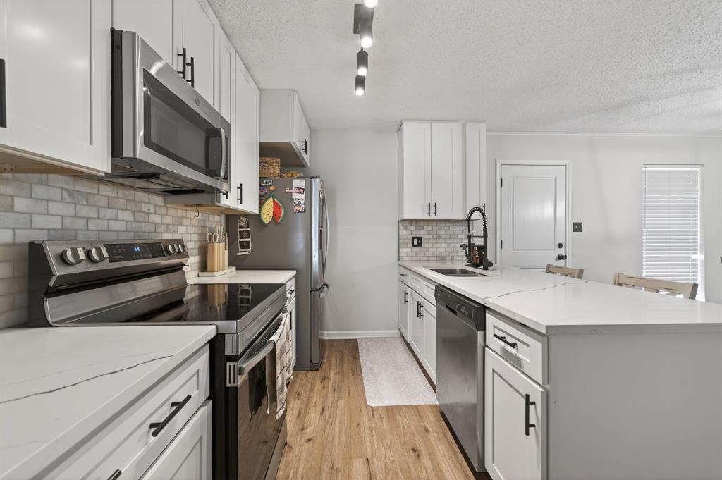11474 Farm To Market 3094 Scurry, TX 75158 - Photo 12 of 40 a kitchen with stainless steel appliances a stove sink microwave and cabinets
