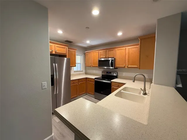 a kitchen with stainless steel appliances a refrigerator sink stove microwave and cabinets