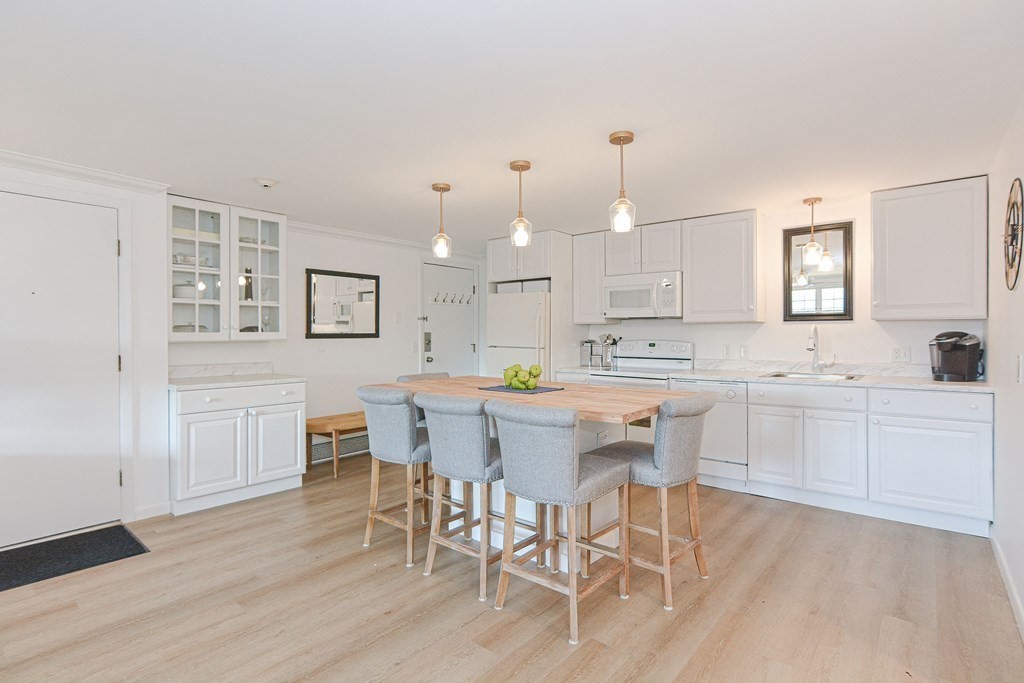 a kitchen with a dining table chairs cabinets wooden floor and appliances