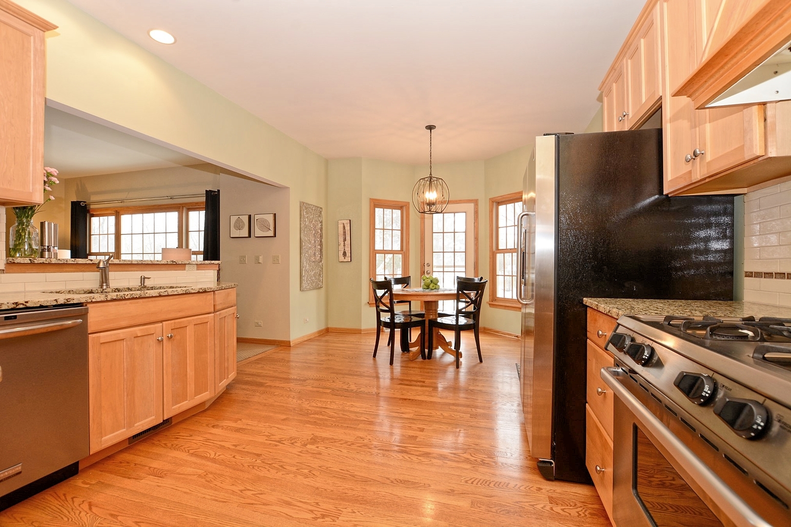916 Merrill New Road Sugar Grove, IL 60554 - Photo 4 of 23 a kitchen with stainless steel appliances granite countertop a stove top oven a sink a dining table and chairs with wooden floor