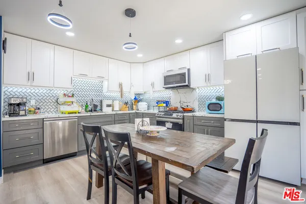 a kitchen with a table chairs refrigerator and microwave