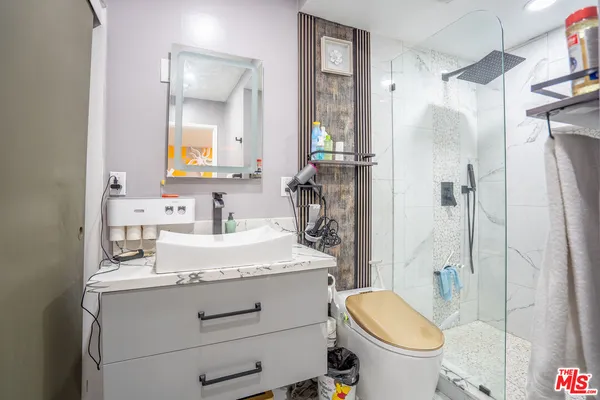 a bathroom with a granite countertop sink toilet mirror and shower