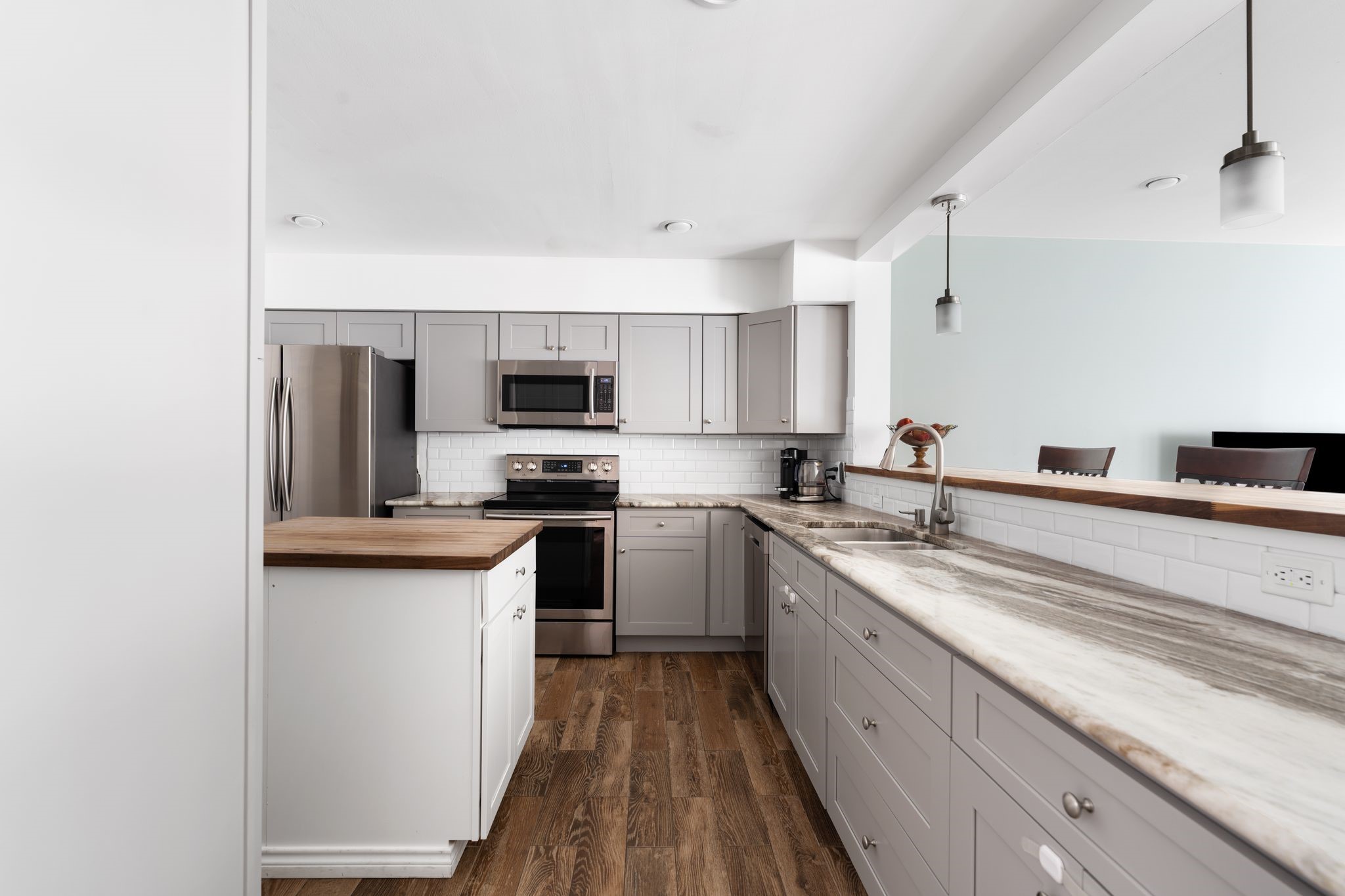 2612 Yupon Street Houston, TX 77006 - Photo 3 of 40 Open concept kitchen design created by removing the original wall, allowing seamless flow into the living area with gray cabinetry, granite countertops, stainless steel appliances, and a wood topped island for added warmth and function.