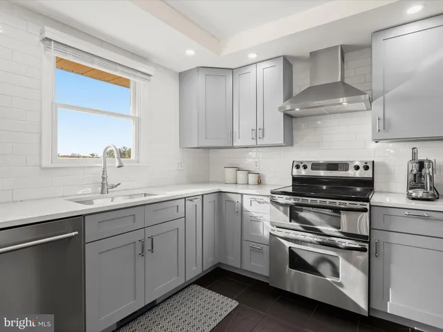 a kitchen with stainless steel appliances a stove a sink and white cabinets