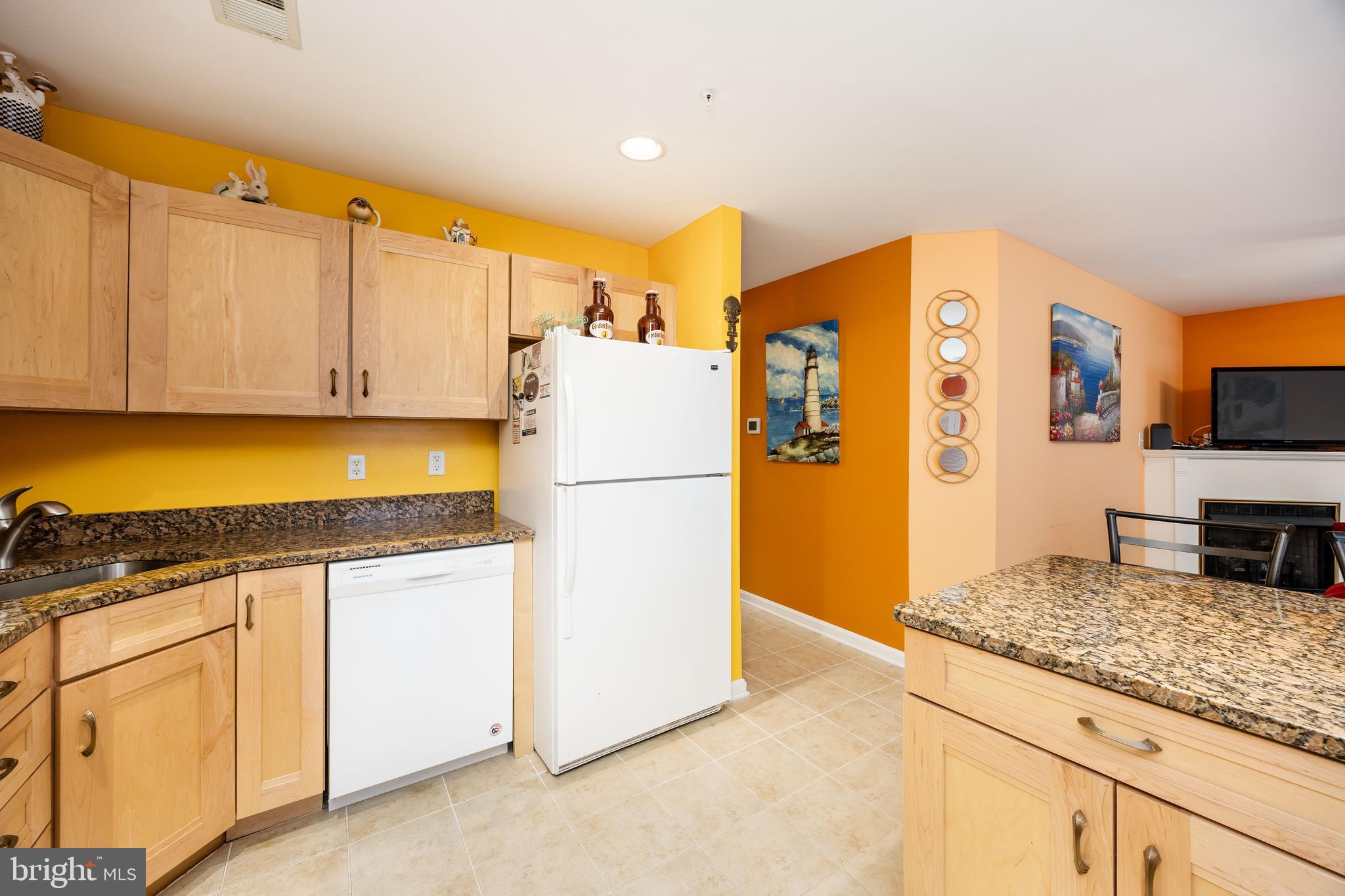 11427 Manklin Creek Road, Unit 7 Ocean Pines, MD 21811 - Photo 11 of 42 a kitchen with granite countertop a refrigerator a stove and white cabinets with wooden floor