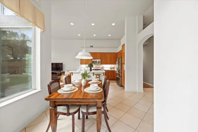 a kitchen with stainless steel appliances kitchen island granite countertop a refrigerator a stove a sink and a dining table