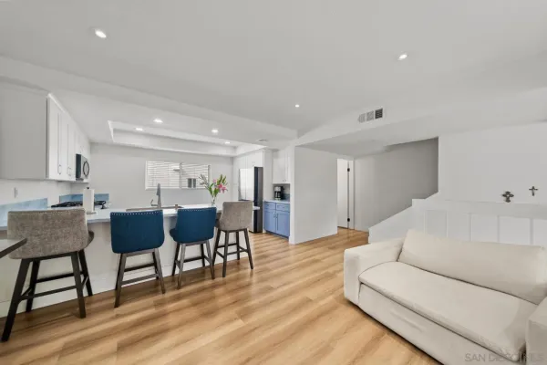a living room with furniture a wooden floor and a kitchen view