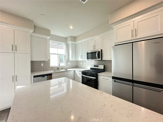 a kitchen with granite countertop stainless steel appliances a refrigerator a stove a sink a center island and cabinets