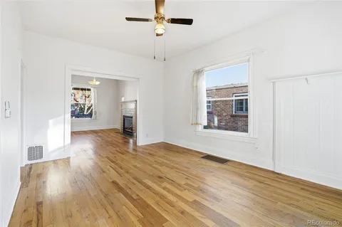 a view of an empty room with window and wooden floor