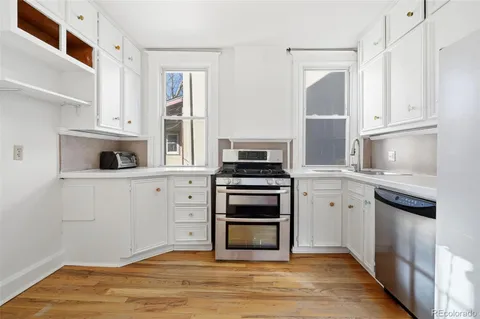 a kitchen with cabinets stainless steel appliances and wooden floor