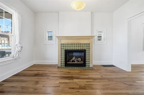 a view of an empty room with wooden floor fireplace and a window