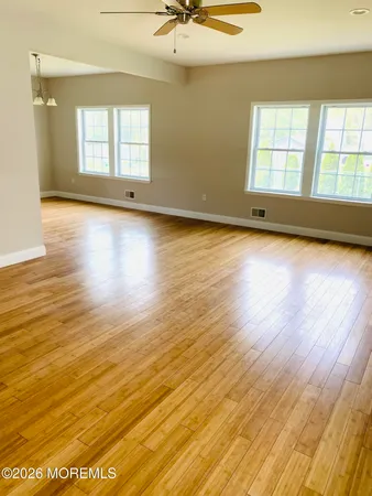 an empty room with wooden floor and windows
