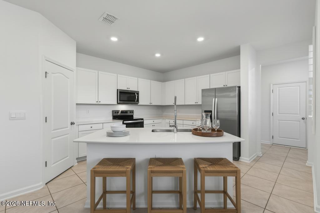 45 Seaport Breeze Road St. Augustine, FL 32095 - Photo 14 of 88 a kitchen with stainless steel appliances granite countertop a table chairs sink refrigerator and cabinets