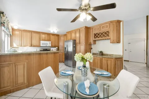 a kitchen with stainless steel appliances kitchen island granite countertop a dining table chairs and a refrigerator