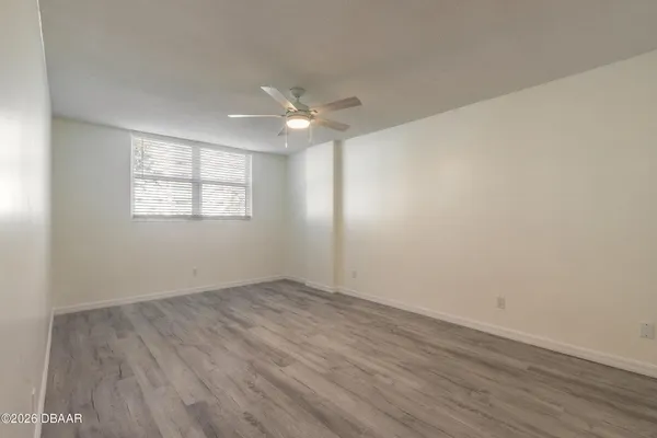 an empty room with wooden floor chandelier fan and windows
