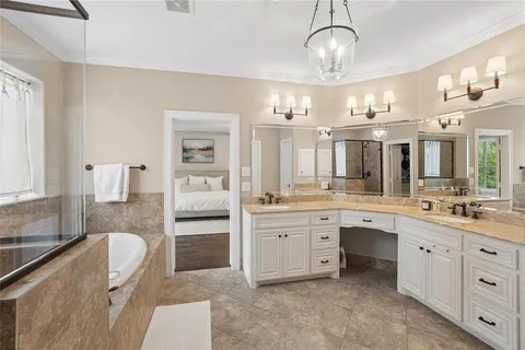 a spacious en suite bathroom with a granite countertop sink mirror and bathtub