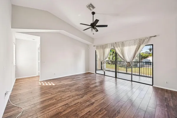 a view of empty room with wooden floor and fan