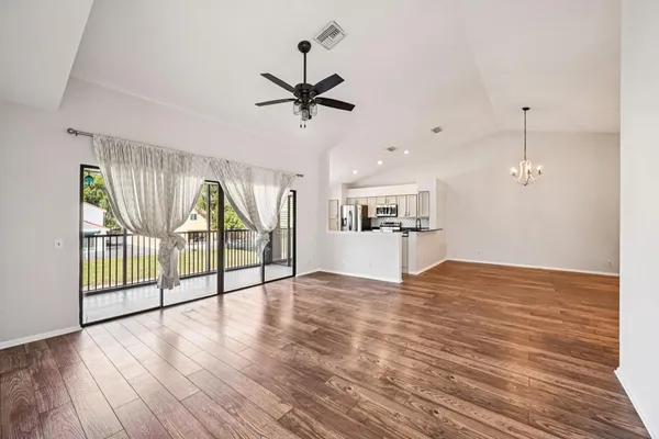 a view of empty room with wooden floor and fan