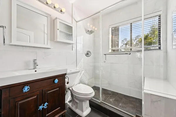 a bathroom with a sink a toilet and shower