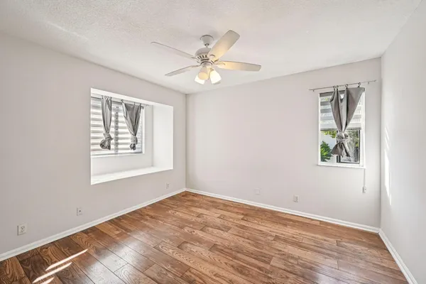 a view of an empty room with window and wooden floor