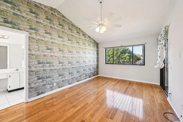 a view of empty room with wooden floor and fan