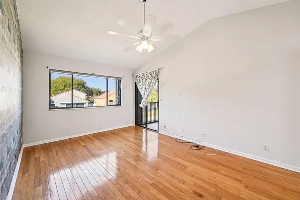 a view of empty room with wooden floor and fan