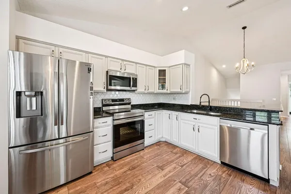 a kitchen with stainless steel appliances granite countertop a refrigerator a stove a sink and a microwave