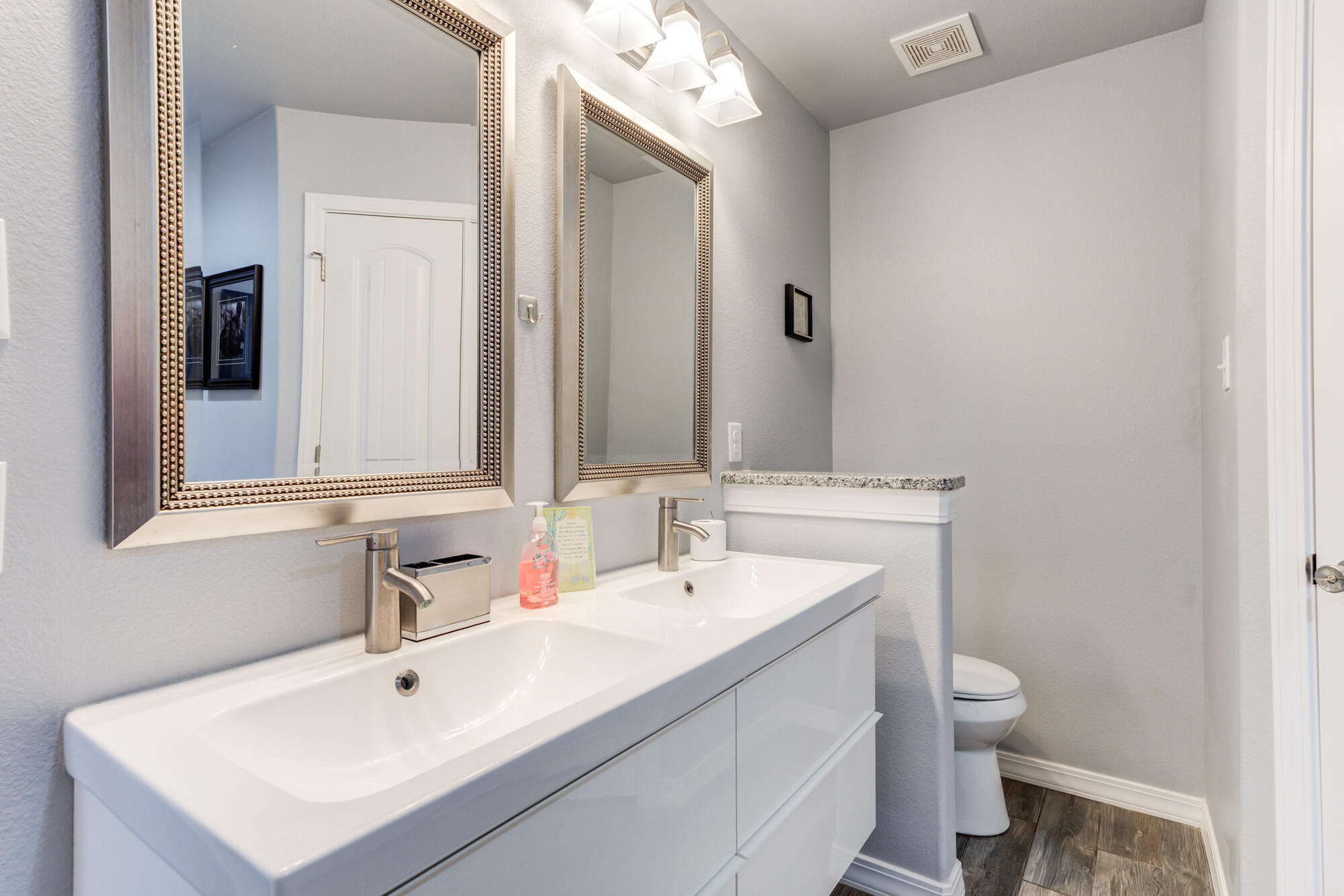 8801 15th Street Lubbock, TX 79416 - Photo 11 of 32 a bathroom with a sink a toilet and a mirror