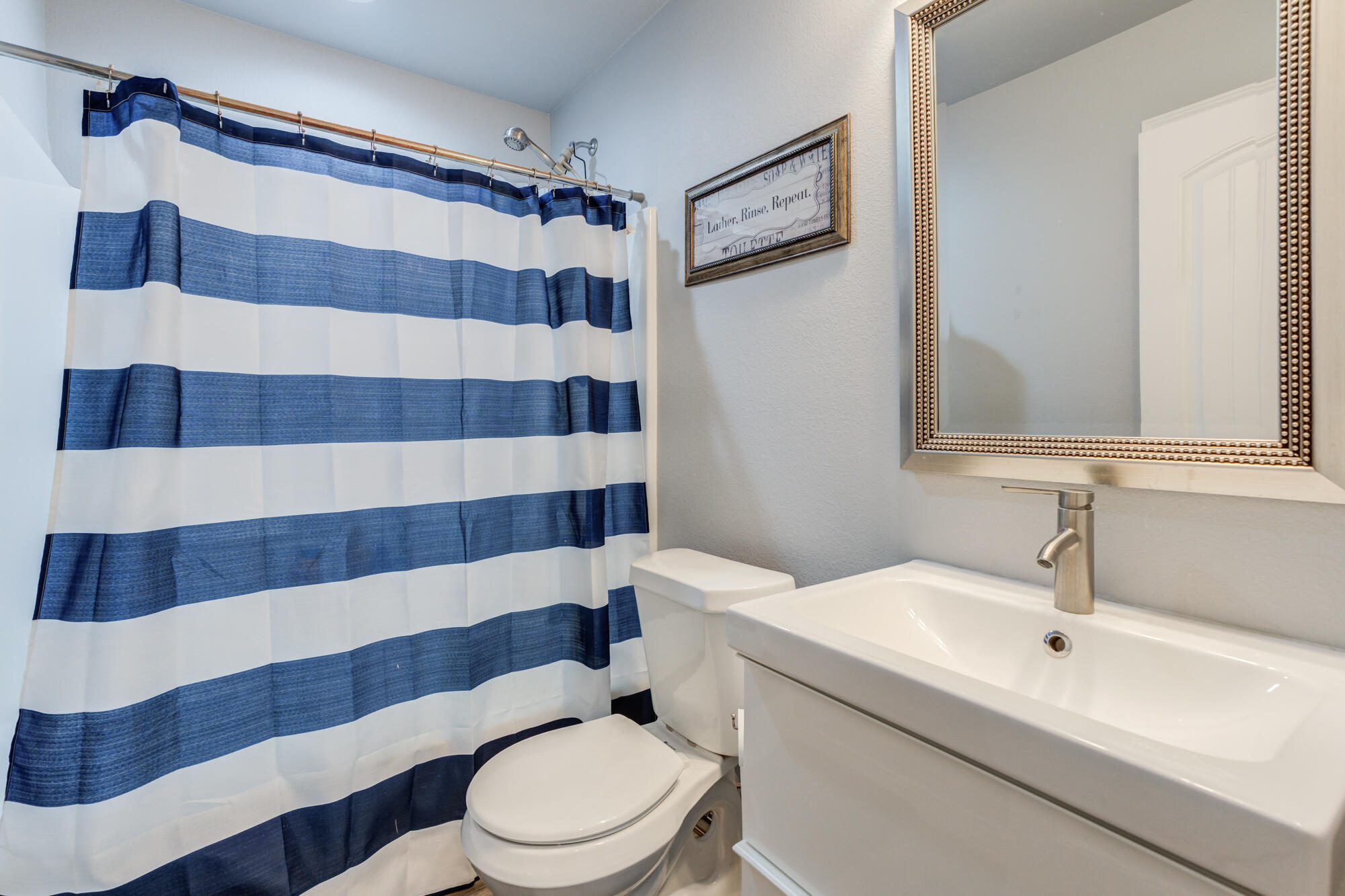 8801 15th Street Lubbock, TX 79416 - Photo 26 of 32 a bathroom with a sink a toilet a shower and a mirror