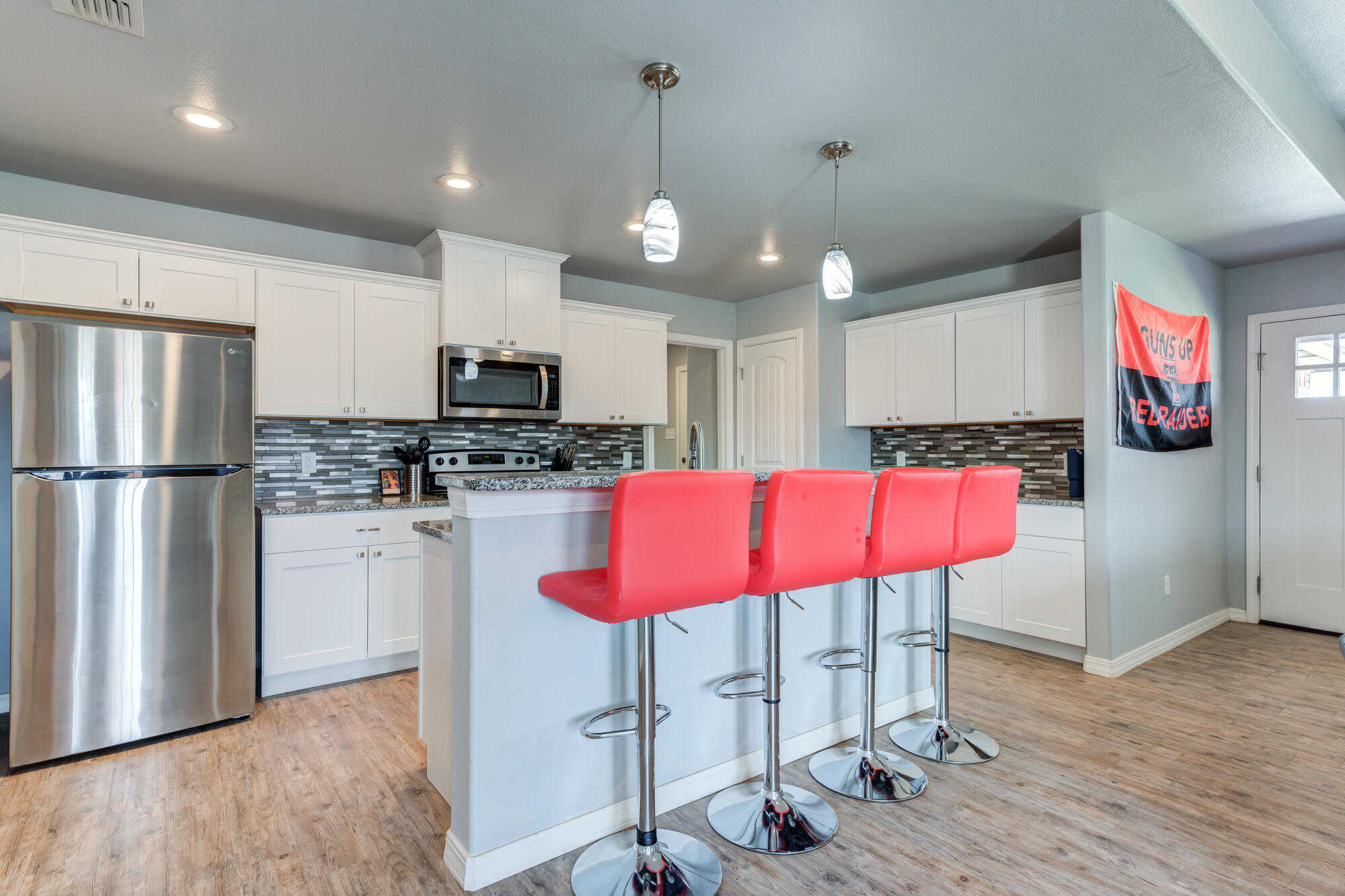 8801 15th Street Lubbock, TX 79416 - Photo 4 of 32 a kitchen with stainless steel appliances granite countertop a refrigerator a stove a sink dishwasher and a dining table with wooden floor