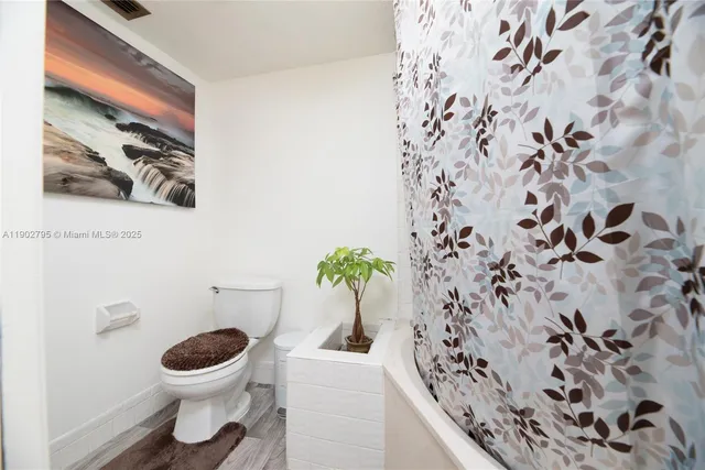 a white toilet sitting next to a shower curtain