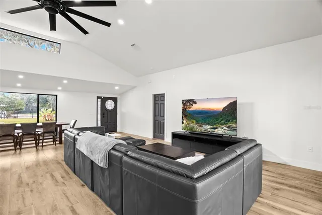 a large kitchen with stainless steel appliances a large counter space a sink dishwasher a dining table and chairs with wooden floor