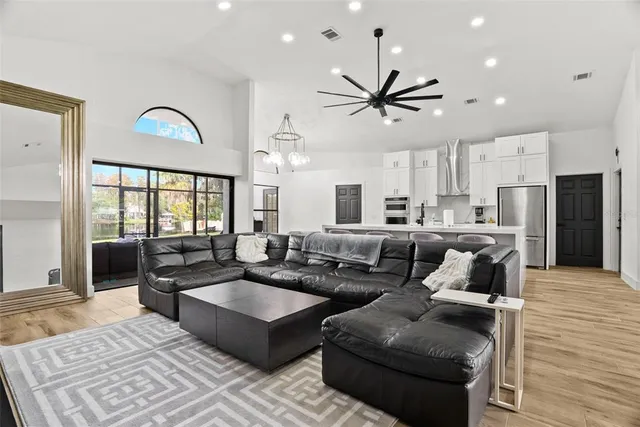 a living room with couches and kitchen view with wooden floor
