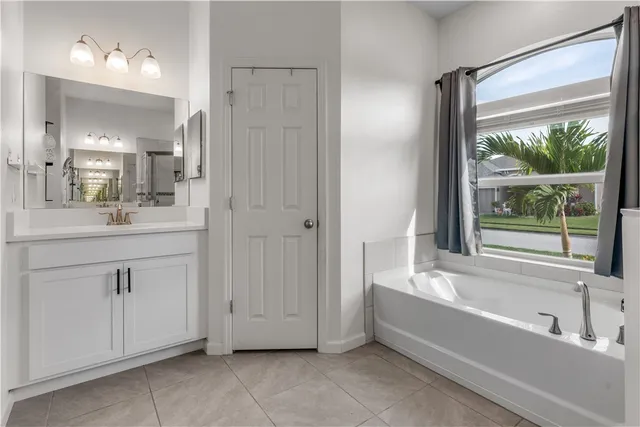 a bathroom with a bathtub a double vanity sink and mirror