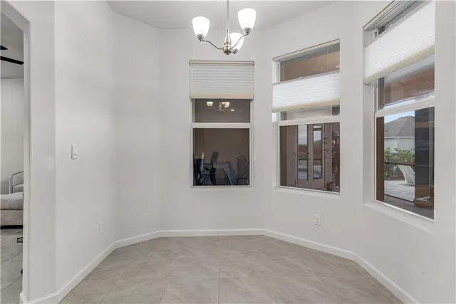 en empty room with a fireplace and chandelier