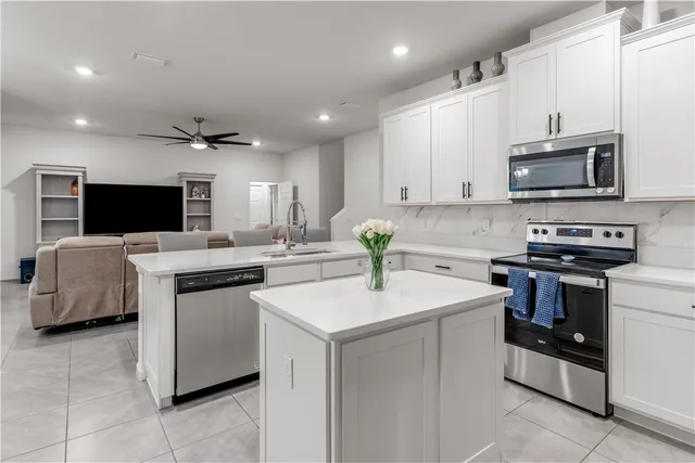 a kitchen with stainless steel appliances kitchen island granite countertop a sink dishwasher stove and microwave with wooden cabinets