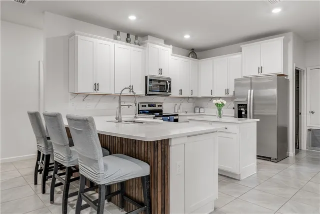a kitchen with stainless steel appliances a refrigerator a stove a sink and white cabinets