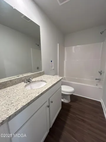 a bathroom with a granite countertop sink a toilet and a bathtub