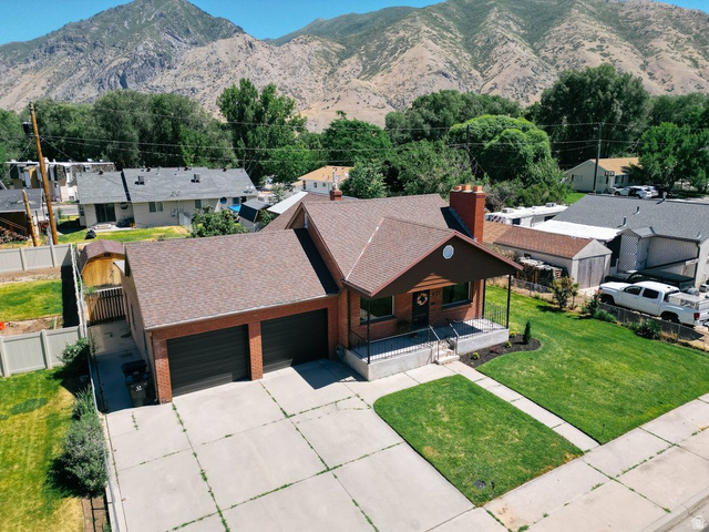 673 East 700 South Springville, UT 84663 - Photo 7 of 43 Brick facade residence featuring a two-car garage, covered porch entry, and a paved driveway