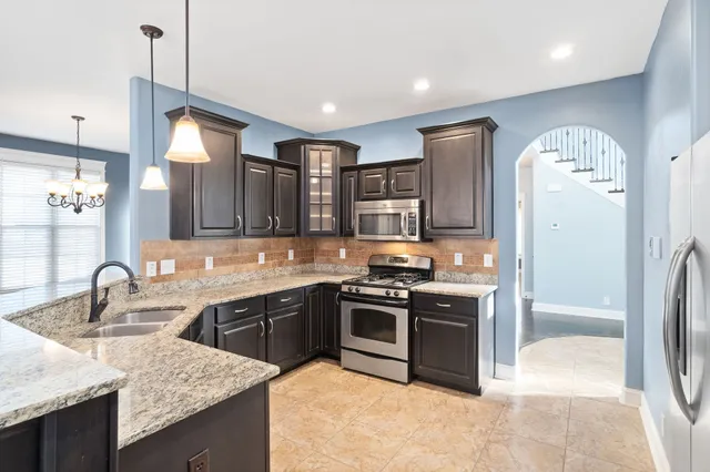 a kitchen with stainless steel appliances granite countertop a sink a stove a refrigerator and island