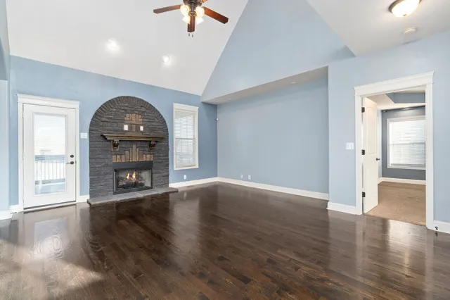 an empty room with wooden floor fireplace and windows