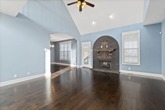 an empty room with wooden floor chandelier and windows
