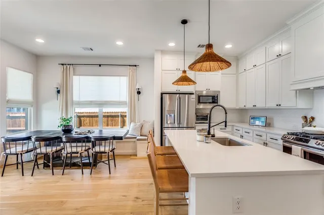 a kitchen with stainless steel appliances a table chairs sink and cabinets