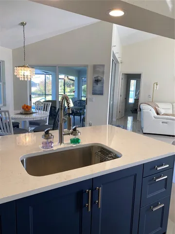 a large white kitchen with a sink a window and stainless steel appliances