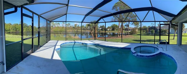 a view of pool with a table and chair under an umbrella