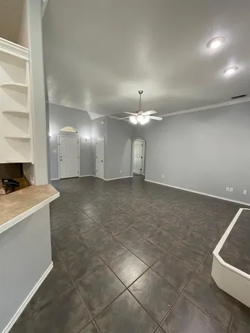 an empty room with chandelier fan and windows