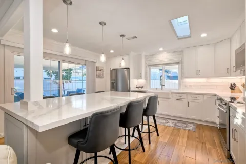 a kitchen with stainless steel appliances a dining table chairs and wooden floor