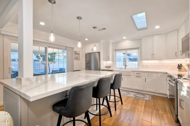 a kitchen with stainless steel appliances a dining table chairs and wooden floor